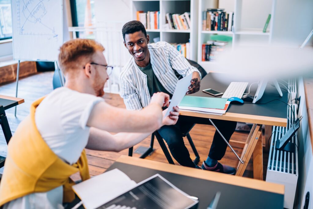 Cheerful black man helping colleague with data